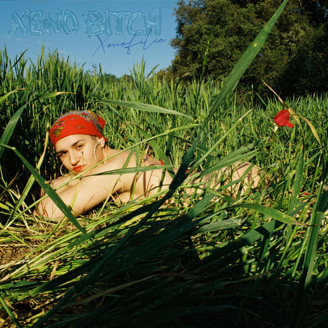 Portada del EP Xenofilia del artista de rap Xeno Bitch. Aparece tumbado sobre césped, mirando de frente, desnudo con un pañuelo rojo en la cabeza y una rosa en el culo.